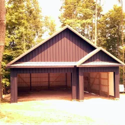 A post frame building with two garage bays sitting in the daytime sun